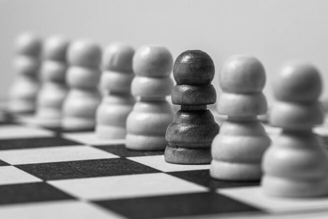 Mustavalkoinen kuva shakkinappuloista pelilaudalla