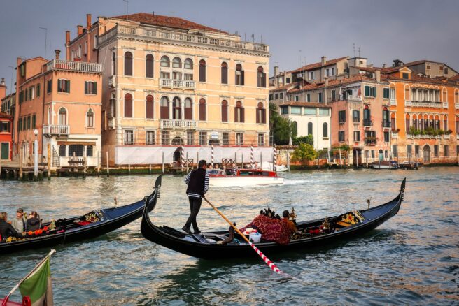 Maisema Venetsiasta, etualalla kaksi gondolia joiden kyydissä turisteja