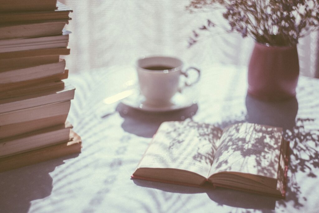 Kirjoja ja kahvikuppi aurinkoisella kesäisellä pöydällä
