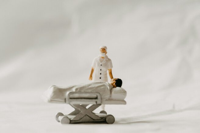 Lääkäri ja sängyssä makaava potilas miniatyyrihahmoina