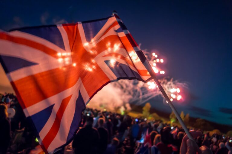 Iltakuva, jossa Union Jack -lipun taustalla näkyy ilotulitus