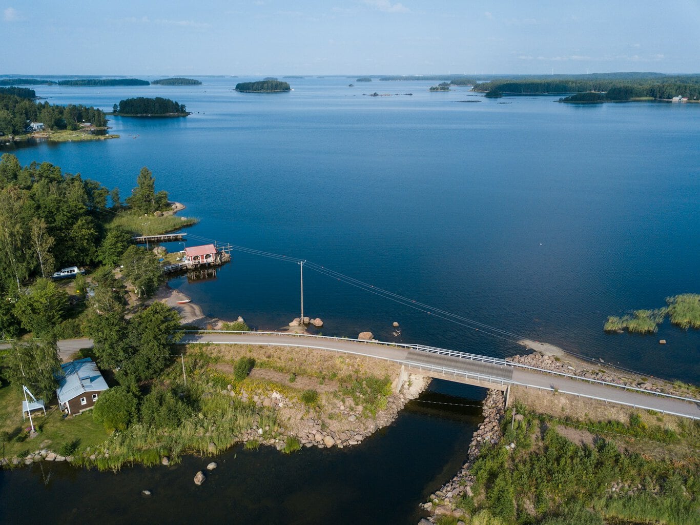 Kesäinen järvimaisema, jossa etualalla silta ja mökkejä